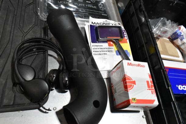 Lot of various items in black poly bin, including black floor mats, headphones, Magnifyn magnifier, and MotoRad box.