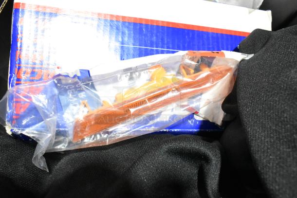 Lot of various items in a black poly bin, including floor mats and headphones. Items sealed in plastic bags. Box in background.