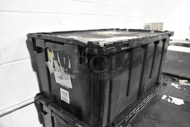 Black poly bin containing various items including floor mats and cable ties. Bin has visible labels and signs of wear.