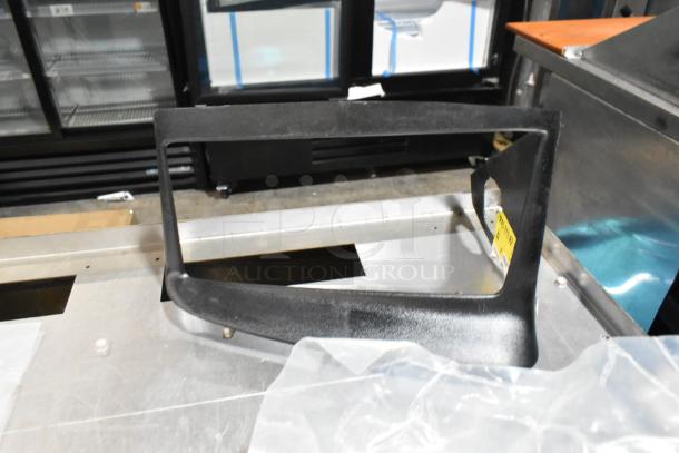 Black poly bin containing various items including floor mats and cable ties. Industrial setting with metal surfaces.