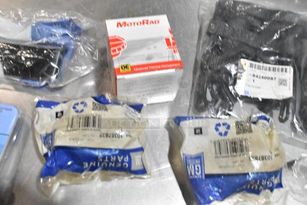 Lot of various items, including wheel locks and 23305978 stabilizer shaft insulator, in black poly bin. Packaged GM parts visible.