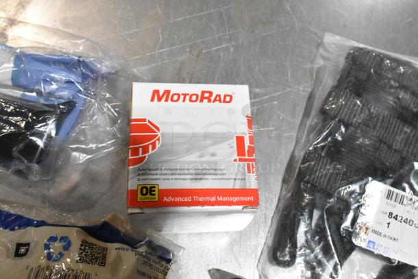 Lot of miscellaneous items in a black poly bin, including a MotoRad box with thermal management parts, wheel locks, and stabilizer shaft insulator.