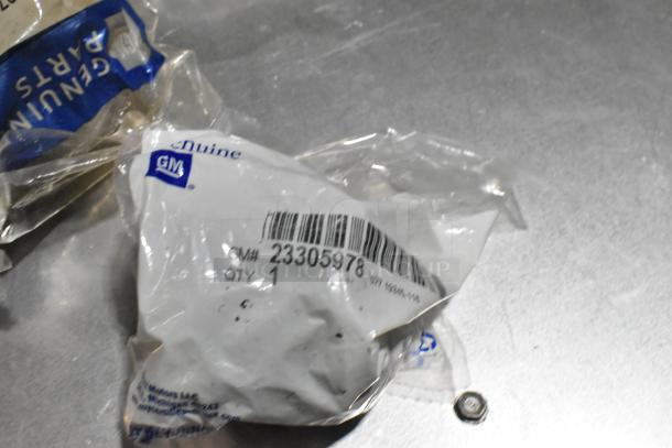 Lot of various items in black poly bin, including GM Genuine Parts #23305978 stabilizer shaft insulator and wheel locks.