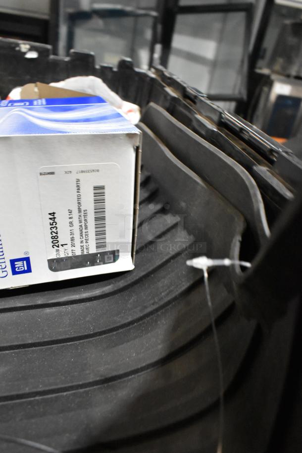 Lot of various items in black poly bin, including GM oil filter box with part number 20823544 and GM 84126999 emblem.