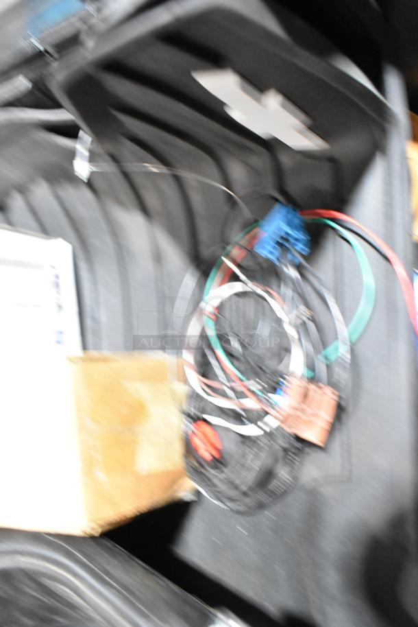 Lot of miscellaneous items in a black poly bin, includes oil filter and GM 84126999 emblem. Mixed condition.