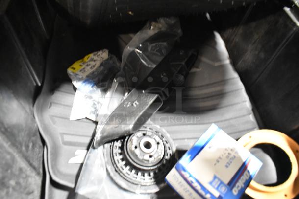Lot of various items in black poly bin, including oil filter and GM 84126999 emblem, assorted in condition.