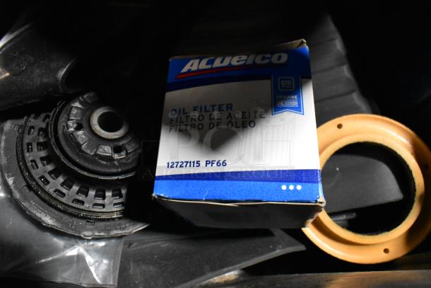 Lot with AcDelco oil filter, GM 84126999 emblem, and assorted items in black poly bin; various automotive components.