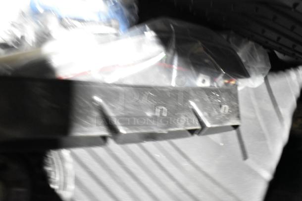 Blurred image showing a black poly bin containing various items, possibly including an oil filter and GM 84126999 emblem.