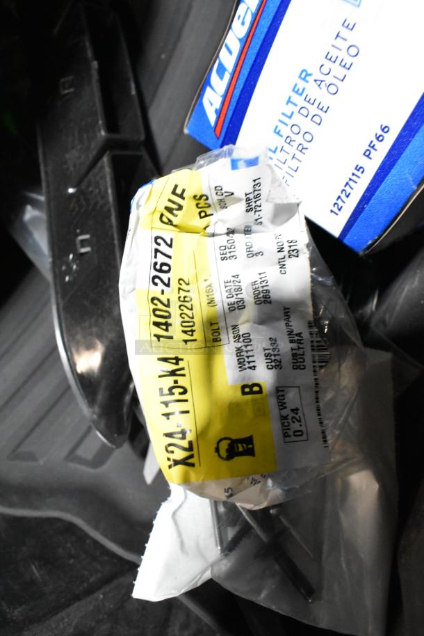 Lot with various items including ACDelco oil filter box, GM 84126999 emblem, in a black poly bin. Tags detail parts info.