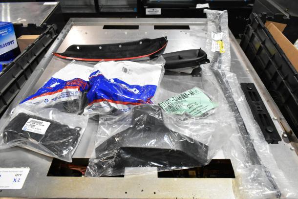 Lot of various items, including GM 84713664 door handles, in a black poly bin. Items in original packaging, assorted conditions.