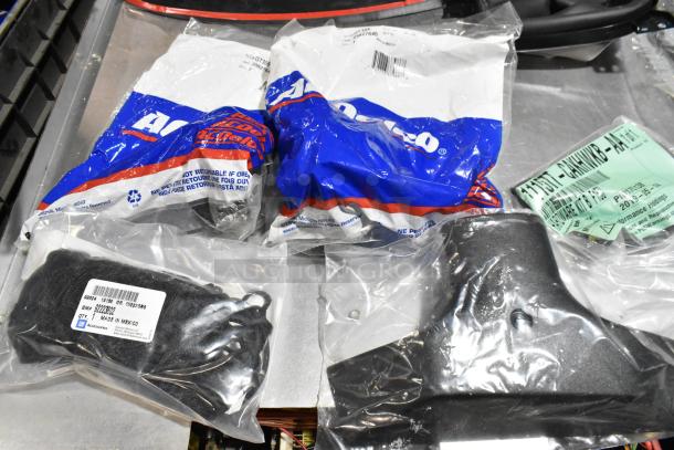 Lot of various items in a black poly bin, including GM 84713664 door handles. Packaged in original bags.
