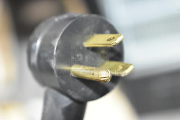 Close-up of a plug for a 2019 Habco SE18 metal commercial cooler, showing its prongs and black casing.