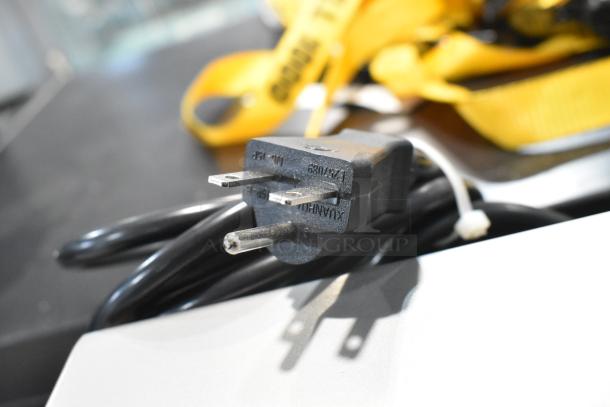 Close-up of the plug for a Sirman 40806206F electric meat mixer, 220 volts. Partial view with background cords visible.