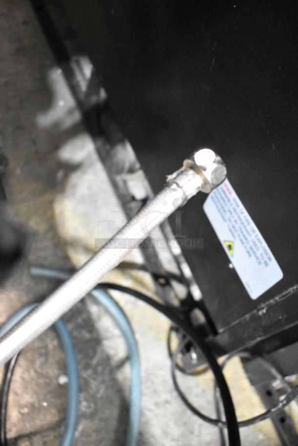 Close-up of Estella ECEM3/N3 espresso machine part with visible hose connection. Scratches and manufacturer's label visible.