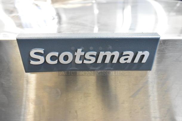 Scotsman MC0830MR-32A stainless steel ice machine close-up, featuring brand logo; new with scratches.
