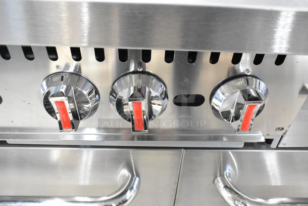 Stainless steel controls of a new 2025 Cooking Performance Group 351S60GS24L commercial range, showing red-handled knobs and oven handles.