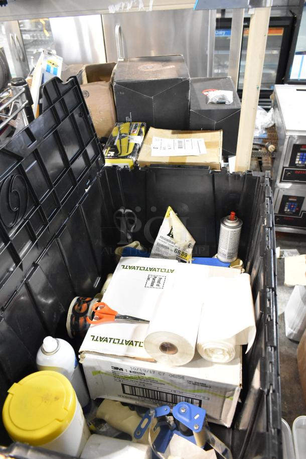 Lot of various items including scissors in a black poly bin. Contains boxed items, rolls, and spray can. Mixed condition.