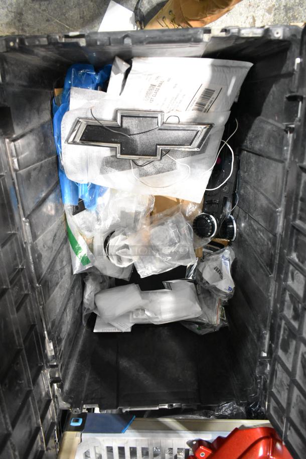 Black poly bin filled with assorted items, including a prominent Chevy emblem and various packaged materials.