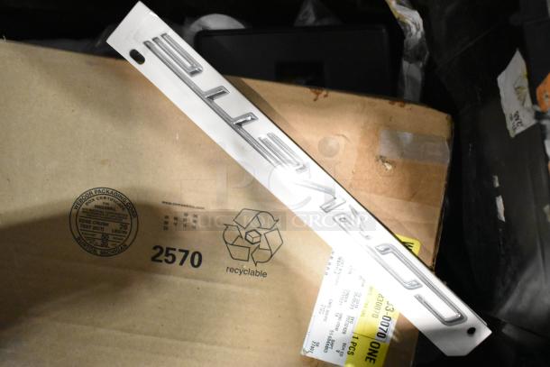 Lot of items with a Corvette emblem in black poly bin, includes cardboard box with shipping label, emblem appears in good condition.