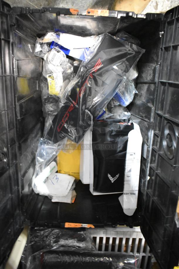 Black poly bin containing various items including a Corvette emblem. Mixed contents, visible labels, and packaging.