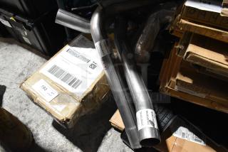 Steel pipes and various items stacked with boxed packaging. Visible labels indicate manufacturing details. Auction lot of 9.