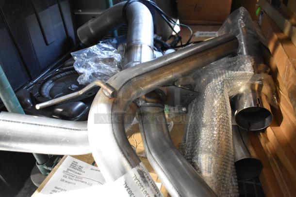 Various automotive pipes in mixed materials, some wrapped in bubble wrap; includes labels and packing slips.