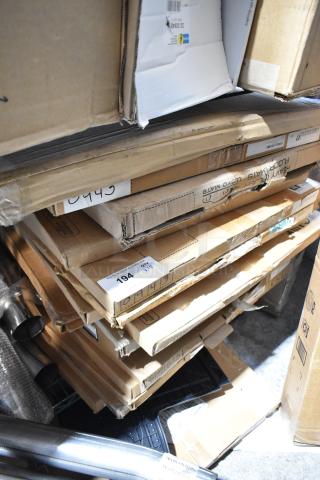 Stack of 18 boxed items including car mats. Various labels and numbers visible. Items appear in boxed, unused condition.