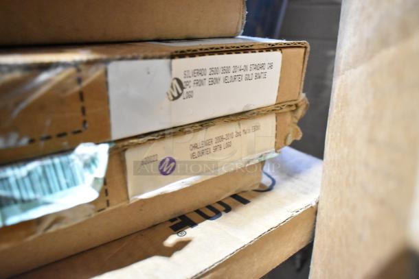 Stack of boxed car mats and accessories featuring labels for Silverado and Challenger models, in new condition.