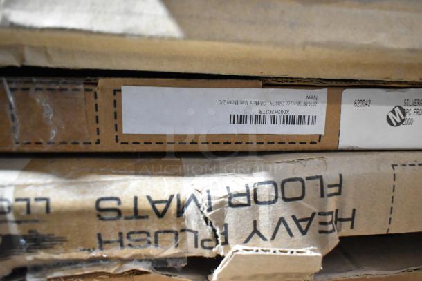 Cardboard boxes labeled 'Heavy Plush Floor Mats' and 'Cab Floor Mats Ebony' stacked, indicating car mat sets.