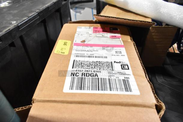 Box filled with assorted items including car mats and coils, shipping labels from Fleetwood, PA visible, overall condition unknown.