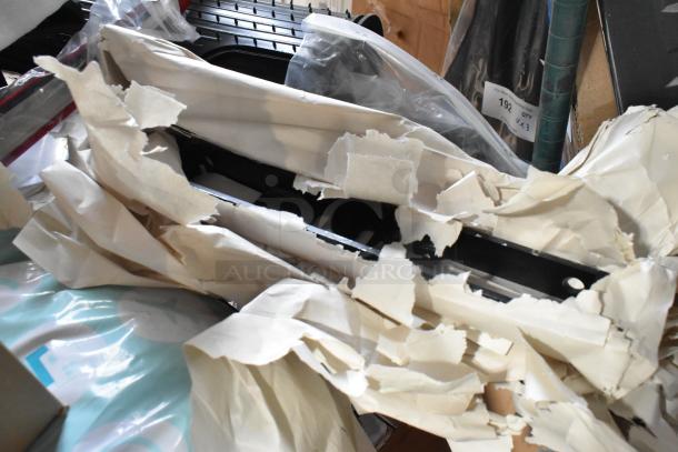 Tiered lot of assorted items including car mats and coils, wrapped in paper, visible packaging and labels. Mixed condition.