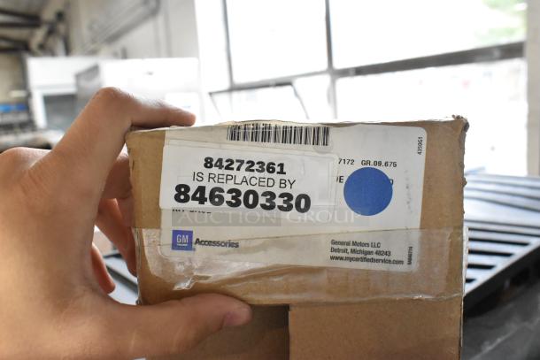 Box labeled GM Accessories, part number 84272361 replaced by 84630330, visible car mats in background.