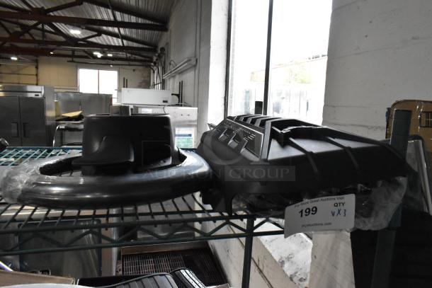 Three assorted items, including a black steering wheel and two black plastic components, on a metal shelf; auction tag "199 QTY x3."
