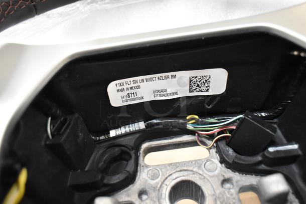 Close-up of a steering wheel's interior showing wiring and label indicating model "Y1XX FLT SW LW W/OCT BZL/SR RM," made in Mexico.