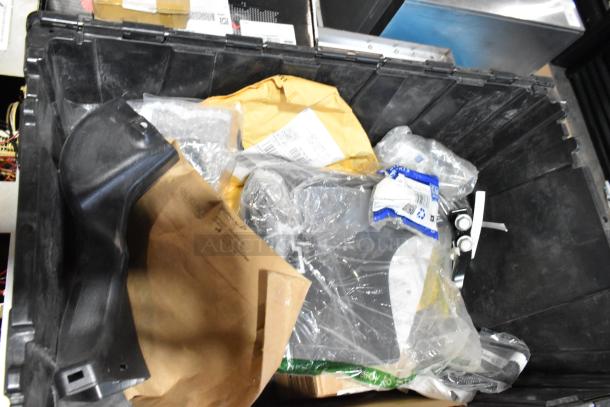 Black poly bin with mixed items, including wheel locks, packaging materials, and various components. Items appear unused.