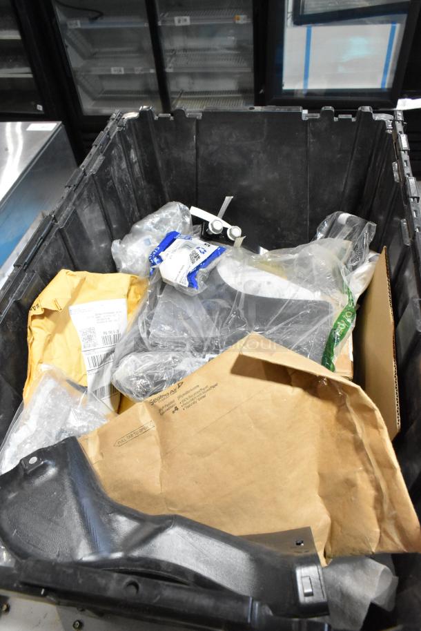 Black poly bin containing assorted items, including packaged wheel locks. Various envelopes and plastic packaging visible.
