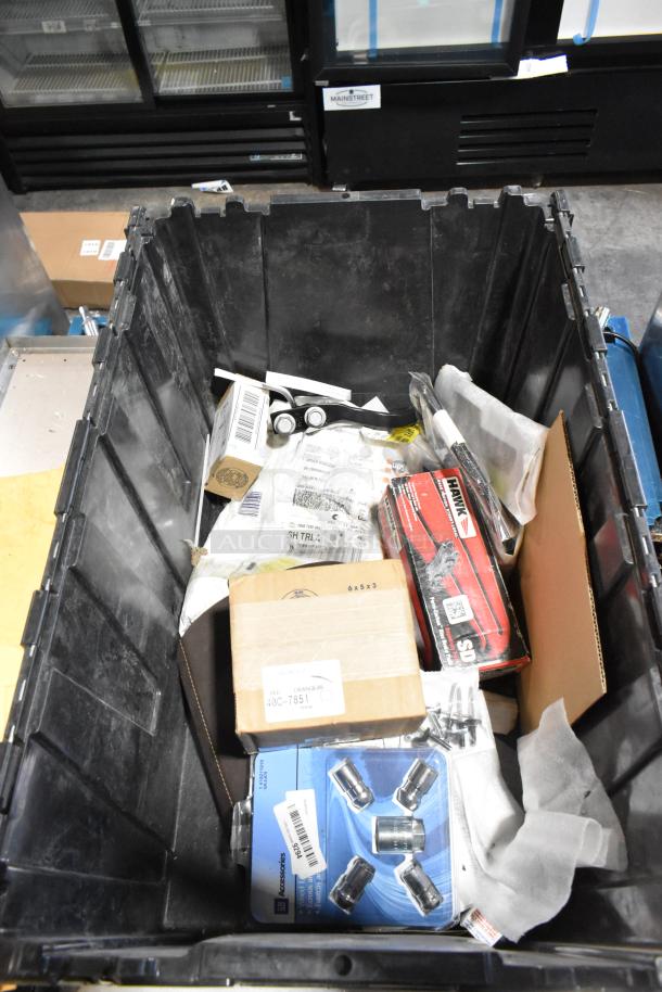 Black poly bin containing various items, including a set of wheel locks, boxes, and assorted packaging. Some items have shipping labels.