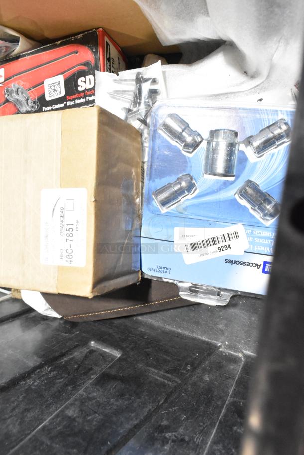 Lot of various items including wheel locks in black poly bin, visible packaging, and labels indicating product details.
