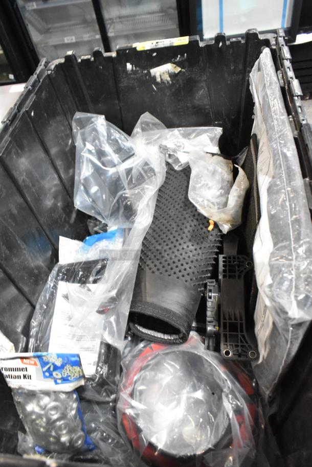 Lot of various automotive parts in a black poly bin, including GM 20823543 front driver side fender ornament. Sealed bags visible.