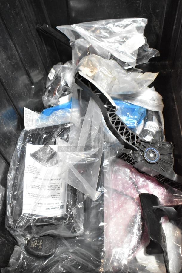 Lot of various items in a black poly bin, including GM 20823543 front driver side fender ornament. Items in mixed condition.