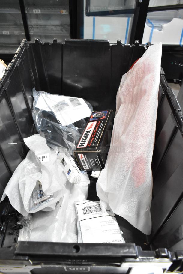 Lot of assorted items in a black poly bin, including Hawk Racing Disc Brake Pads. Various packaging visible. Mixed condition.