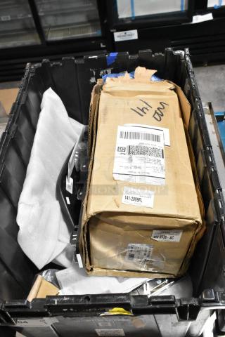 Black poly bin containing assorted items, including a GMC emblem. A labeled cardboard box is also visible inside.