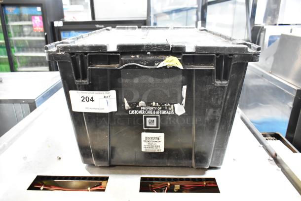 Black poly bin labeled "Property of Customer Care & Aftersales" with a GMC emblem, containing various items, tag number 204.