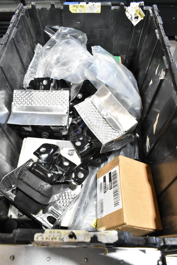 Lot of various items including metal brackets, cardboard box, and packaging materials in black poly bin.