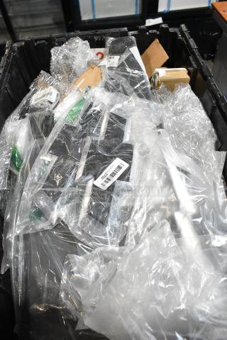 Lot of assorted items in black poly bin, includes wrapped GMC emblem, bubble wrap, various packaging materials.