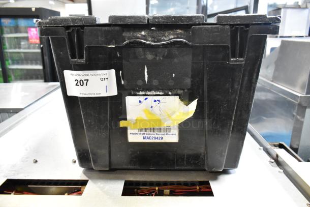 Black poly bin containing various items, including a GMC emblem. Label indicates "Property of GM Customer Care and Aftersales" with code MAC29429. Auction tag "207 QTY 1".