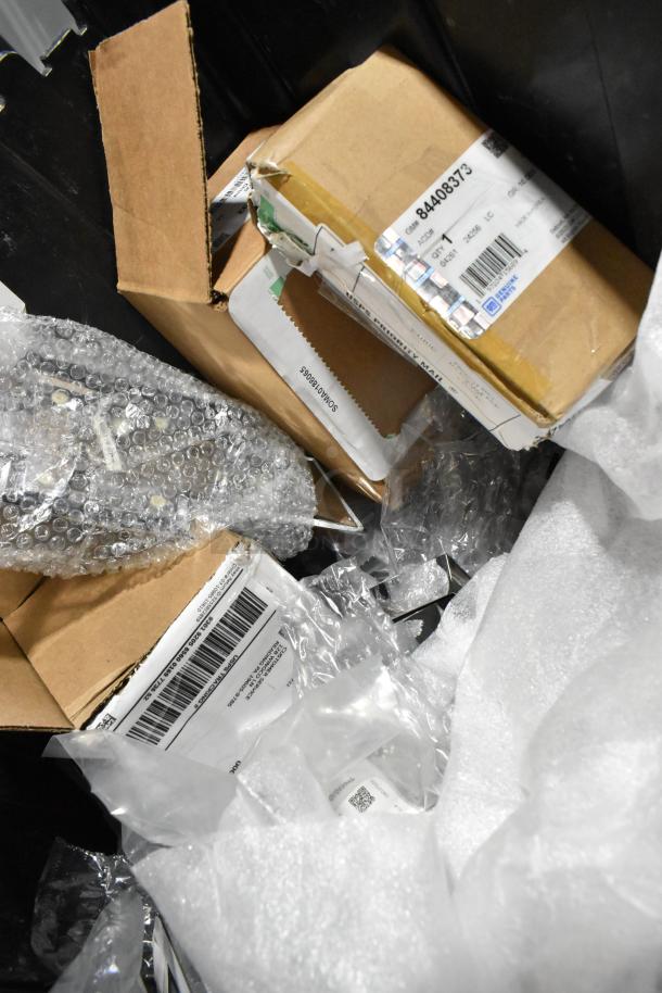 Lot of various items including a GMC emblem in a black poly bin. Items in boxes with shipping labels and bubble wrap.