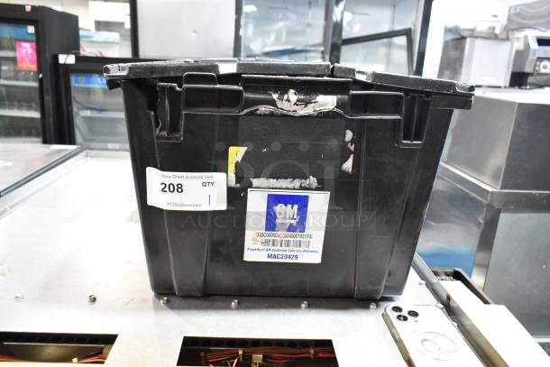 Black poly bin containing a mix of items including a GM 23221725 Universal Tablet Holder. Bin shows GM label and auction tag.