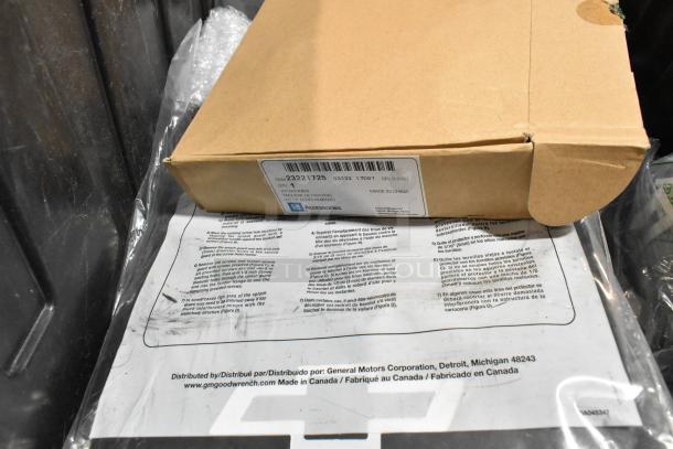 Lot of various items including GM 23221725 Universal Tablet Holder, visible in labeled cardboard box, placed in black poly bin.