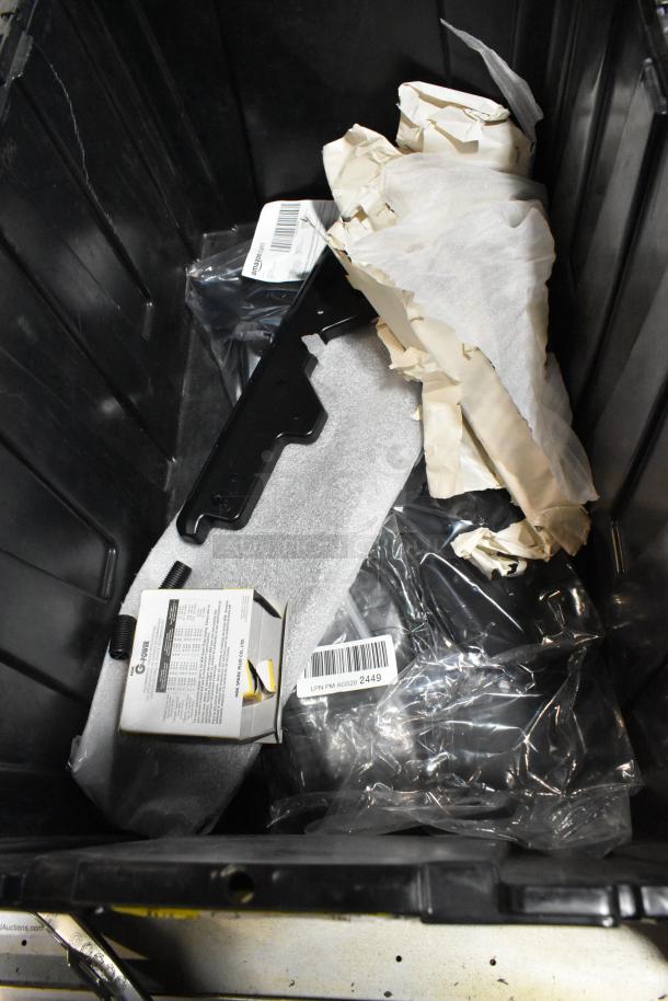 Various items in black poly bin; includes packaging materials, a labeled box, and plastic bag. Condition varies.